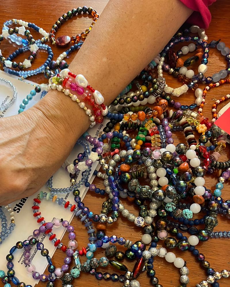 Handmade beaded bracelets from FunShop spread across a table, one wrist wearing several.